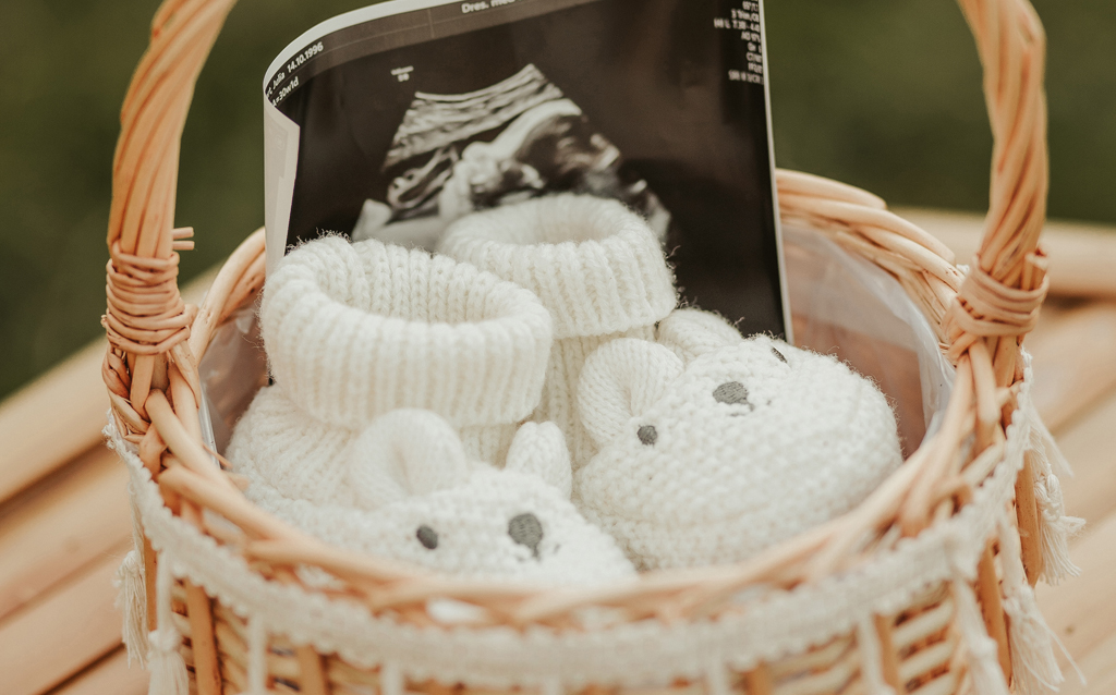 Süße kleine Babyschuhe und Ultraschallbild in Körbchen aus Babybauchshooting am Kaiserstuhl